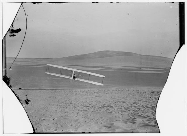 Rear view of Wilbur making a right turn in glide from No. 2 Hill, right wing tipped close to the ground Photo Credit 