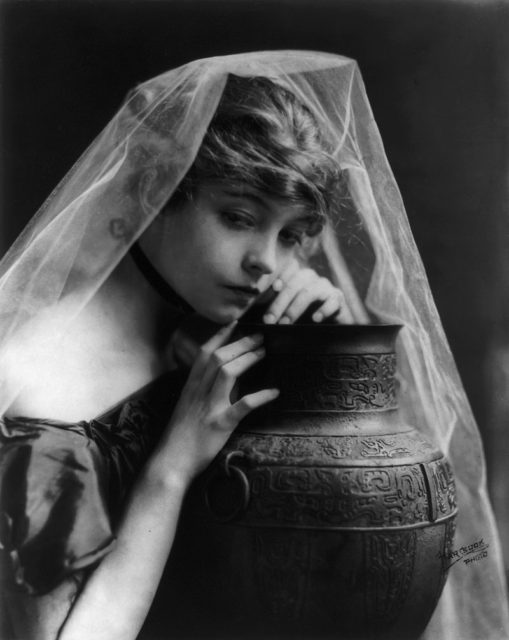 Lillian Gish, head-and-shoulders portrait, facing right, leaning on large pottery vase. Photo Credit 