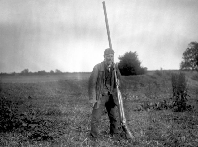 1910. Mr. Snowden Slights with a punt gun.Size comparison of a man and punt gun . Photo Credit 