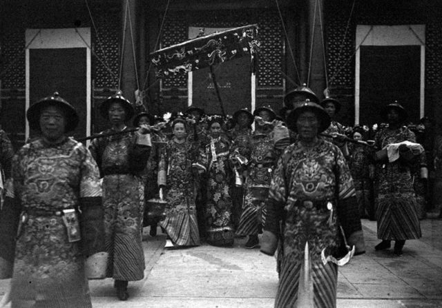 Empress Dowager Cixi holds hands with the fourth daughter of Prince Qing (to her left) and chief palace eunuch Li Lianying (to her right).
