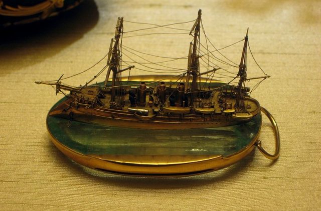 The miniature gold and platinum model of the Russian naval cruiser Pamiat Azova (“Memory of Azov“), set on a piece of aquamarine. Photo Credit