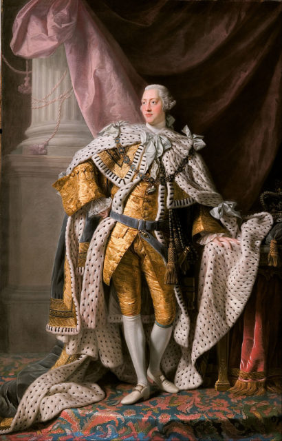 Full-length coronation portrait in oils of a clean-shaven young George in eighteenth-century dress: gold jacket and breeches, ermine cloak, powdered wig, white stockings, and buckled shoes.