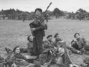 William “Bill” Millin (14 July 1922 – 17 August 2010), playing his pipes for fellow soldiers in 1944.