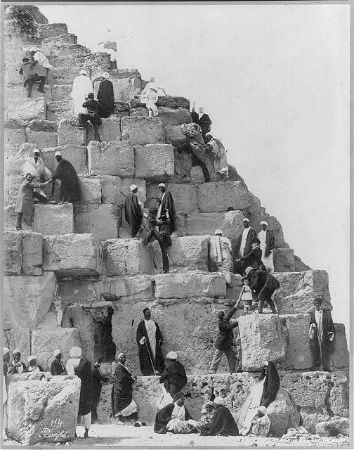 Several people gathered at the base of the Great Pyramid, others climbing Photo Credit 