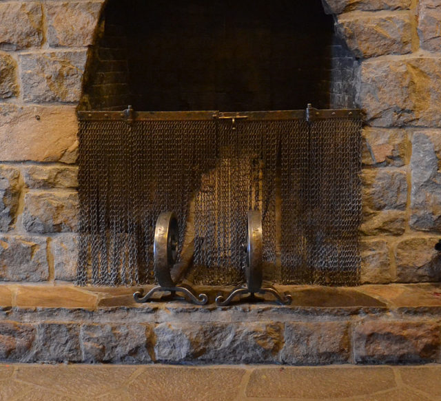 Fire screen made from tire chains and andirons forged from old railroad rails Photo Credit