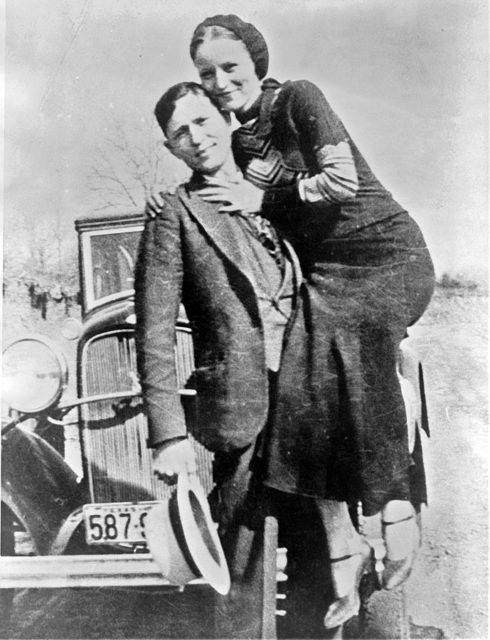 Bonnie and Clyde sometime between 1932 and 1934, posing in front of their famous 1932 Ford V-8 automobile.