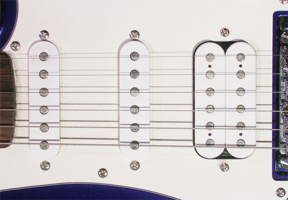 Three pickups mounted in the body of an electric guitar.