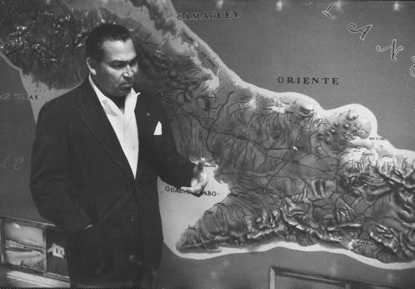 Batista in March 1957, standing next to a map of the Sierra Maestra mountains where Fidel Castro’s rebels were holed-up