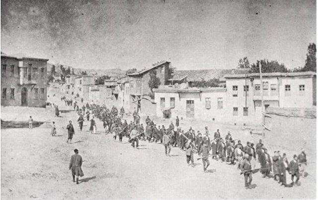 Armenian civilians are marched to a nearby prison in Mezireh by armed Ottoman soldiers. Kharpert, Ottoman Empire, April 1915