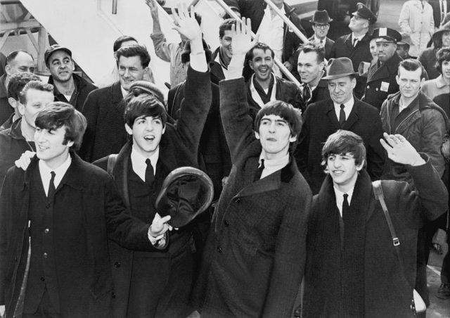 The Beatles wave to fans after arriving at Kennedy Airport