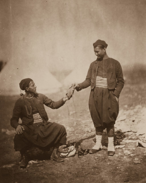 Two French Army Zouaves, light infantry soldiers with distinctive uniforms, share a drink.
