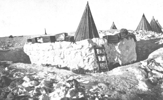 Tents in the Framheim designed to accommodate dogs and the storing of supplies. In the foreground: storage of fresh meat, enclosed snow fence.