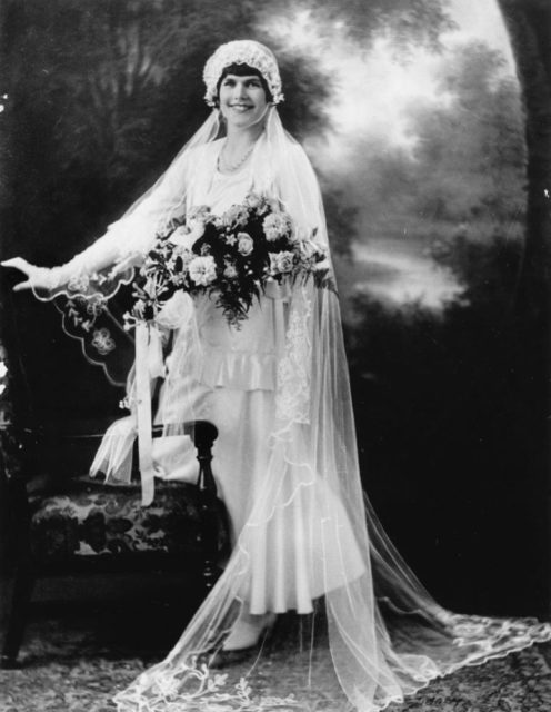 Bride wearing a bias cut, tea-length satin dress, and a flowing embroidered veil.