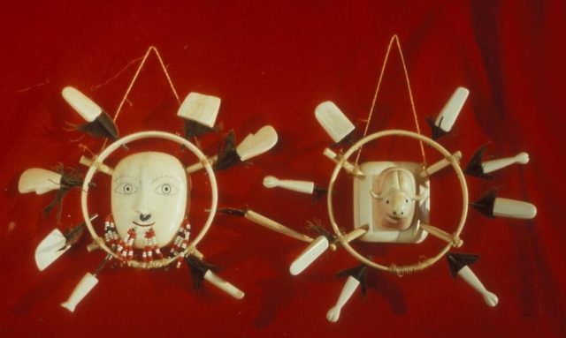 Contemporary stylized ivory single-color mask, ringed with ivory sculpted as a jewel in the circle, on the left with human eyes, musk cattle on the right.