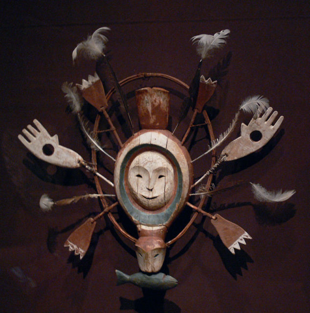 It is painted in three colors (red, blue-green, white), with a wooden ring, a seal with a fish in the mouth, a hole with a big thumb as a jewel attached to the body, and feathers. Dallas Museum of Art, Dallas, Texas, late 19th century.