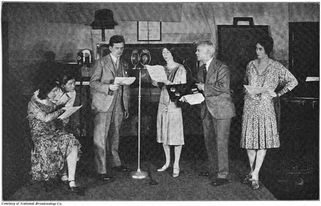 An early sound effects man (right) adding effects to a live radio play in the 1920s. He holds an effects board with which he can simulate ringing telephones and closing doors.