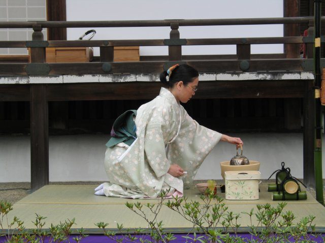 A tea ceremony being performed outdoors with a tetsubin, a brazier, and a tea bowl; a bamboo marker marks the seating position of the host. Author: Stephane D’Alu CC BY-SA 3.0