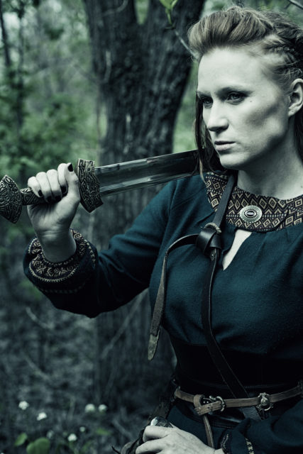 Scandinavian woman with sword posing in a forest