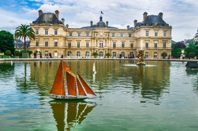 A Remote control sailboat complete with captain and cres navagates the calm waters of the fountain pool at the Luxembourg Garden