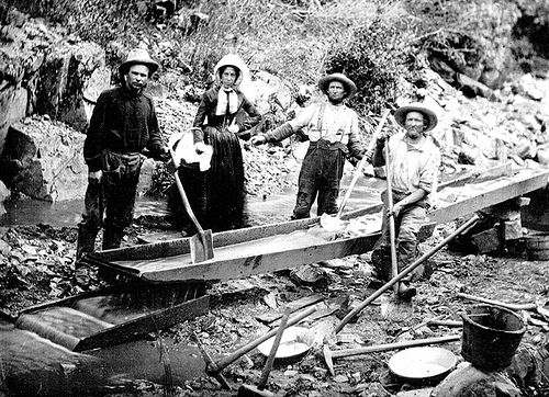 A woman with three men panning for gold during the California Gold Rush
