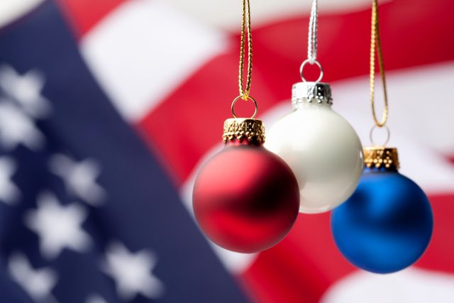 Red, white and blue Christmas ornaments with American flag background.