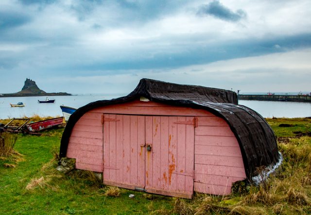 Currough, an old fishing boat now converted to a shed on the shoreline of the Holy Island of Lindisfarne in the North-Eastern county of Northumberland, England.