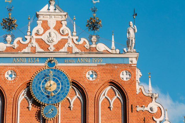 Sculptures On The Facade Of The House Of Blackheads In Riga, Latvia. Famous Landmark. Travel Destination. Town Hall Square. Four Statues Named After Neptune, Agreement, Peace, Mercury. Astronomical Clock and emblems