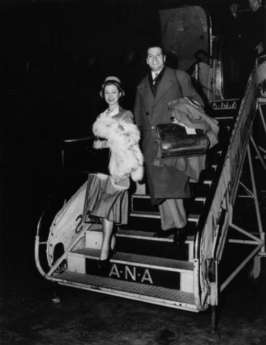 Sir Laurence Olivier and Lady Olivier (Vivien Leigh) smile at he waiting crowd as they step from the plane at Archerfield Aerodrome.