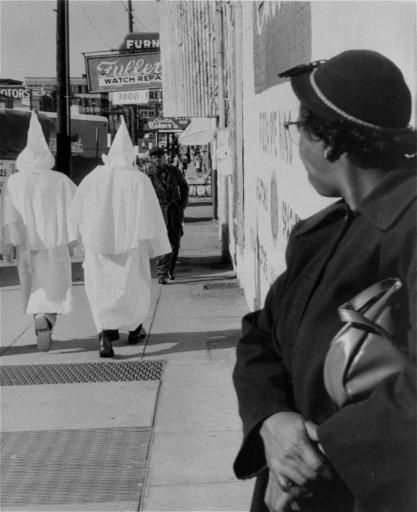 https://www.thevintagenews.com/wp-content/uploads/2015/05/A-woman-watches-as-robed-Ku-Klux-Klansmen-walk-in-downtown-Montgomery-Alabama-prior-to-a-cross-burning-rally-that-night-November-24-1956..jpg