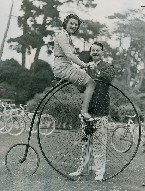 Riding a penny farthing in a skirt and heels, 1930