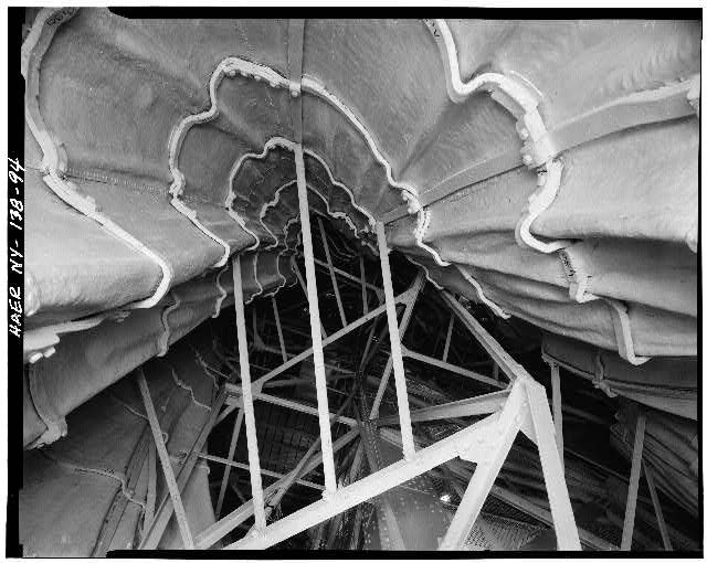 Interior view of east-side of statue looking up showing secondary iron frame and strap-iron armature supporting copper skin of toga. February 1984
