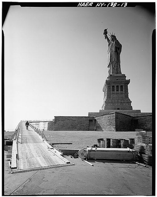 Left-side view looking west showing statue and pedestal with walls of Fort Wood and entrance to construction ramp in foreground. February 1984