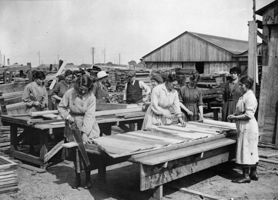 A group of female carpenters work in a lumber yard in France, constructing wooden huts. While they do not have a uniform, all the women appear to be wearing a protective coat or pinafore over their clothing. It is thought this photograph was taken by the British official photographer, John Warwick Brooke. Q.M.A.A.C. stands for Queen Mary's Army Auxiliary Corps. Formed in 1917 to replace the Women's Auxiliary Army Corp, by 1918 around 57,000 women made up the ranks of Q.M.A.A.C. (National Library of Scotland) 