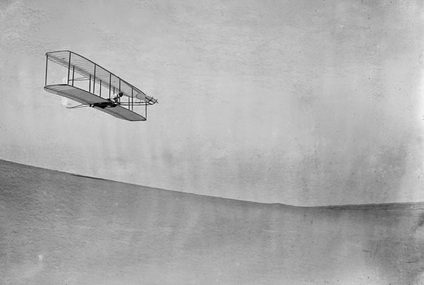 Wilbur Wright pilots a full-size glider down the steep slope of Big Kill Devil Hill in Kitty Hawk, North Carolina, on October 10, 1902. This model was the third iteration of the Wright brothers’ early gliders, equipped with wings that would warp to steer, a rear vertical rudder, and a forward elevator.