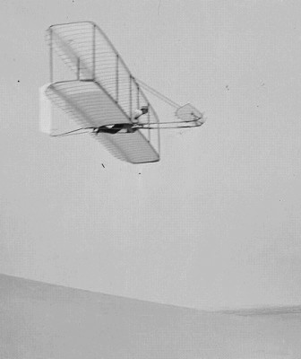 Wilbur Wright pilots the 1902 glider over the Kill Devil Hills, October 10, 1902. The single rear rudder is steerable; it replaced the original fixed double rudder.