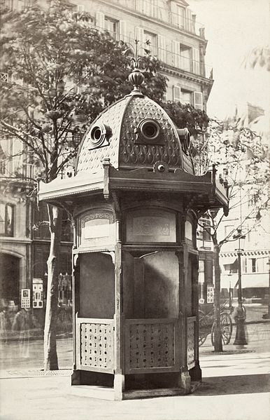 Cast iron urinal with domed roof, on curb of street, Place du Théâtre Français, Paris, France.