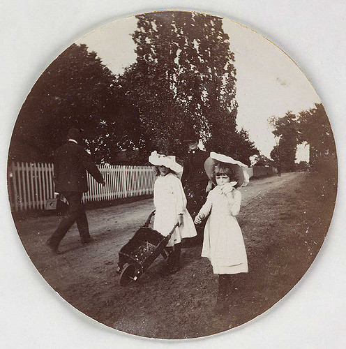 Children walking with a wheelbarrow, about 1890