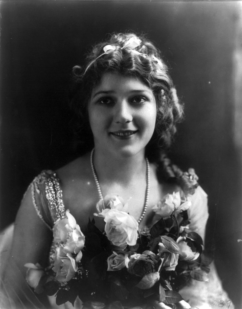 Mary Pickford, head and shoulders portrait, holding flowers, facin g front. .Source