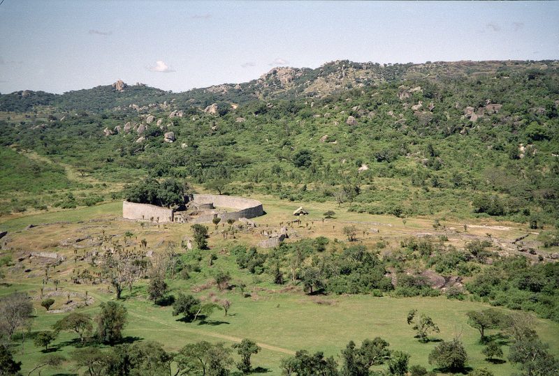 Overview of Great Zimbabwe. The large walled construction is the Great Enclosure. Some remains of the valley complex can be seen in front of it. source