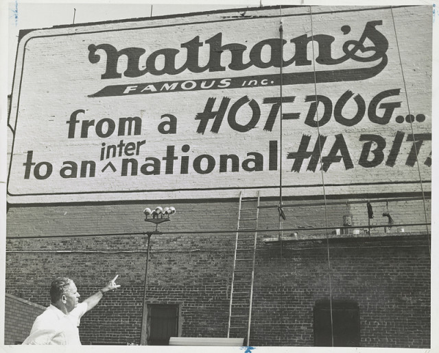 Photograph showing Nathan Handwerker pointing to Nathan’s Hot Dog sign. Library of Congress