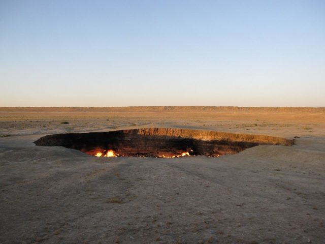 The Soviets were digging for natural gas in 1971, the ground collapsed, and with an explosion was born the Darvaza Gas Crater, burning to this day.Source