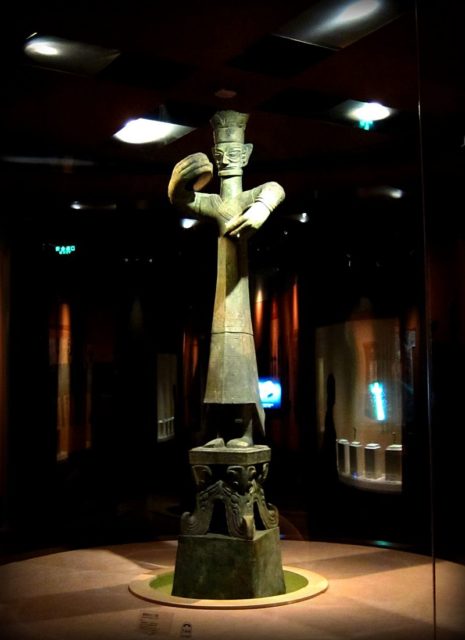 An upright bronze figure representing the high priest Source:By momo - Flickr: Bronze Standing Figure (青銅立人像), CC BY 2.0, https://commons.wikimedia.org/w/index.php?curid=28822127