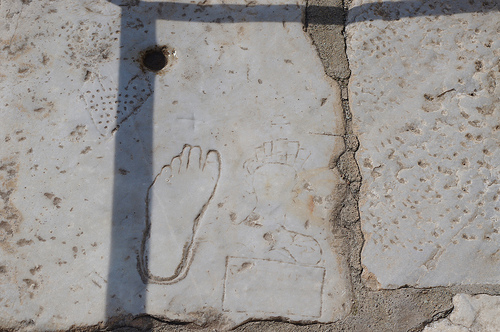 These graffiti carved into the paving of Ephesus' main street actually compose an advertisement for the city's largest brothel. Here you can see a heart, a picture of a woman, a jug of wine on a table, and a foot showing which way to walk. Photo Credit