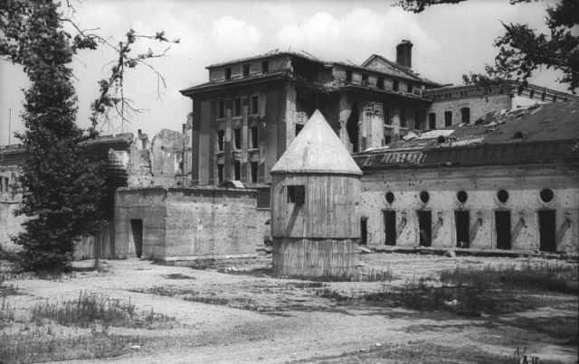 The above-ground portion of the Führerbunker shortly before it was destroyed in 1947. Hitler & Eva Braun’s remains were burnt in a shell crater in front of the emergency exit at the left. The circular structure was for generators and ventilation. Photo by Bundesarchiv, Bild 183-V04744 / CC-BY-SA 3.0