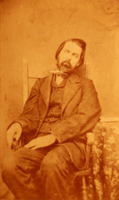 A post-mortem photograph of a middle-aged man. The body is arranged to appear lifelike (c.1860).