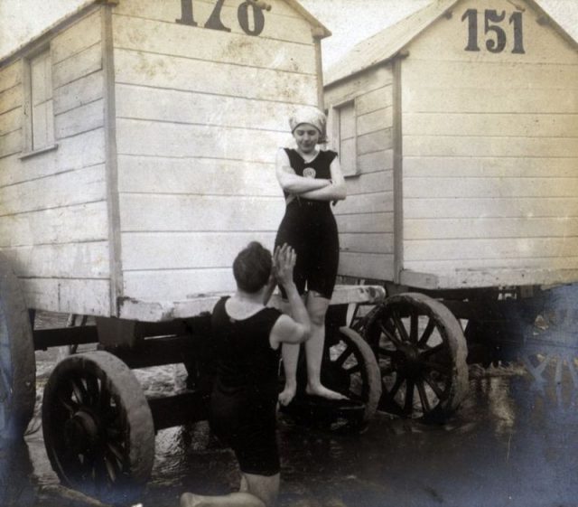 A woman and a man at the Ostend Beach in Belgium. Notice the “bathing machine” in the background, now relics of the Victorian era.