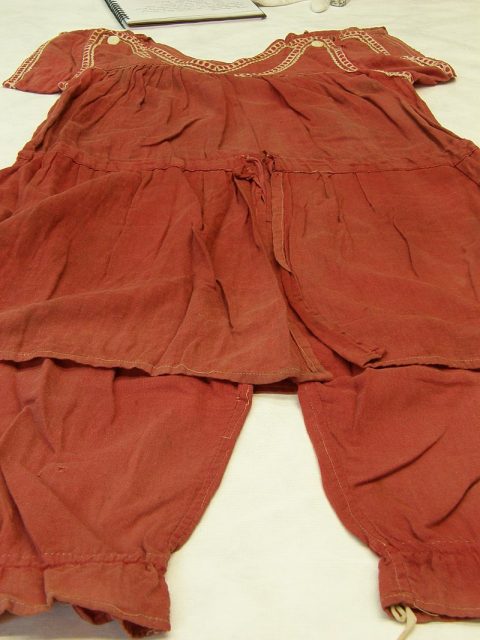 An Edwardian-style bathing suit. Made of twilled cotton, colored red, Photo by Auckland Museum CC-BY 4.0