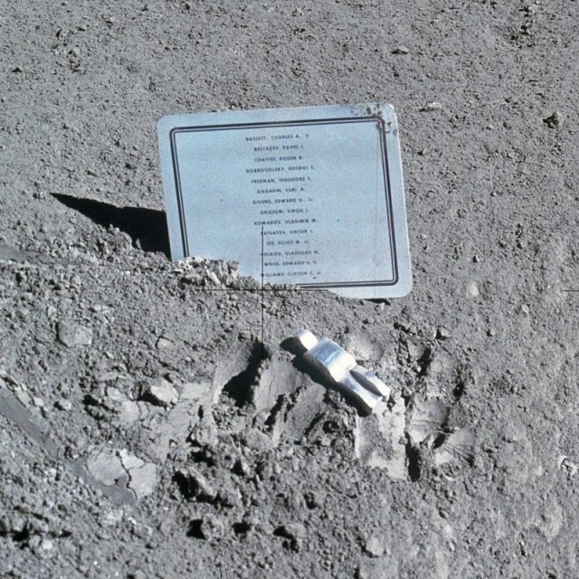 Commemorative plaque and the Fallen Astronaut sculpture left on the Moon during the Apollo 15 mission. The plaque is inscribed with the names of the names of eight American astronauts and six Soviet cosmonauts (including Vladimir Komarov) who died in service.