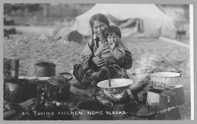 A woman and a child. It is cooking time outdoors. The year is 1916.