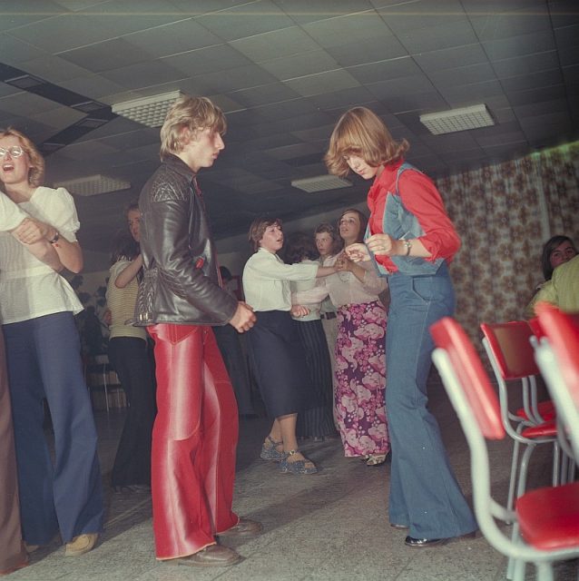 Flared jeans and trousers were popular with both sexes as can be seen at this German disco in 1977. Photo by Deutsche Fotothek‎ CC BY-SA 3.0 de